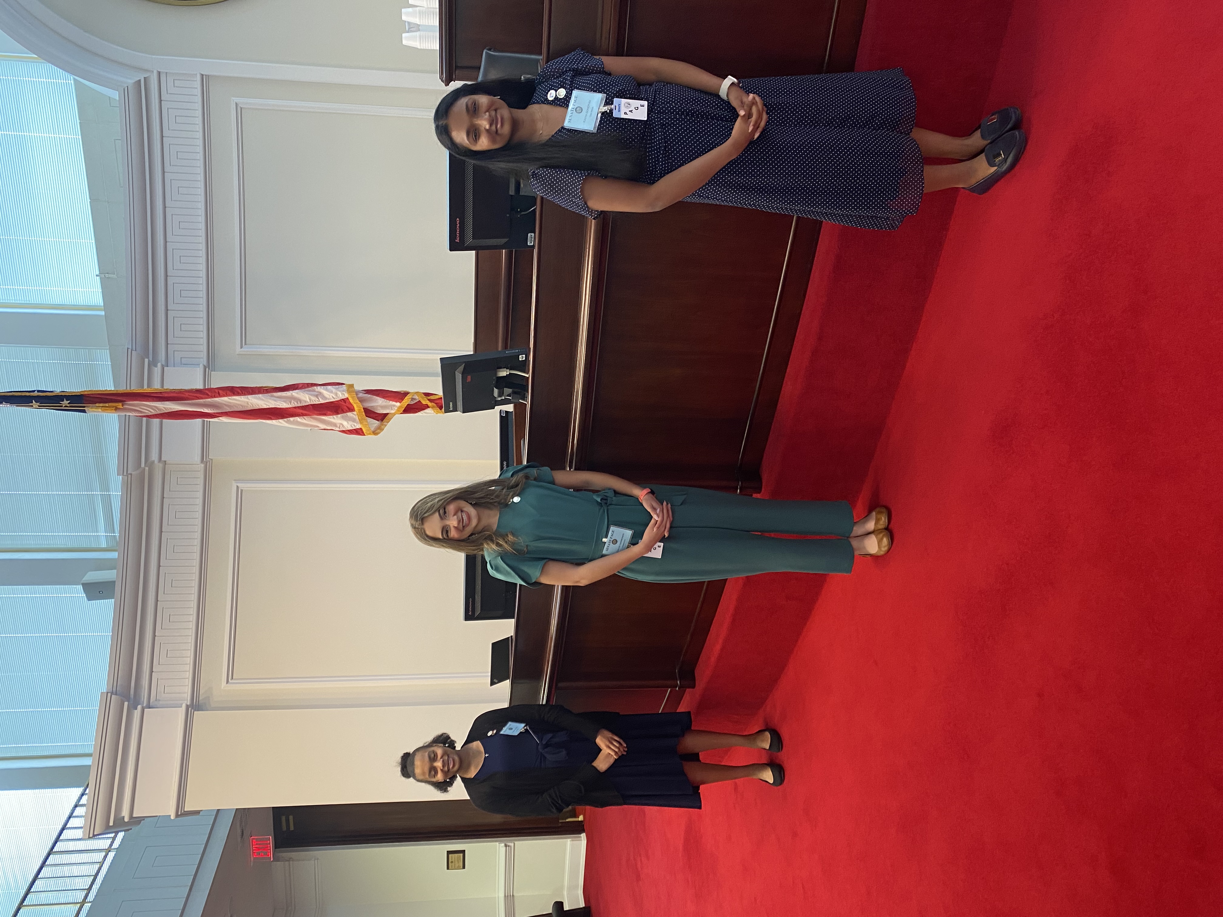 Three Senate Pages standing in front of Senate chamber dais.